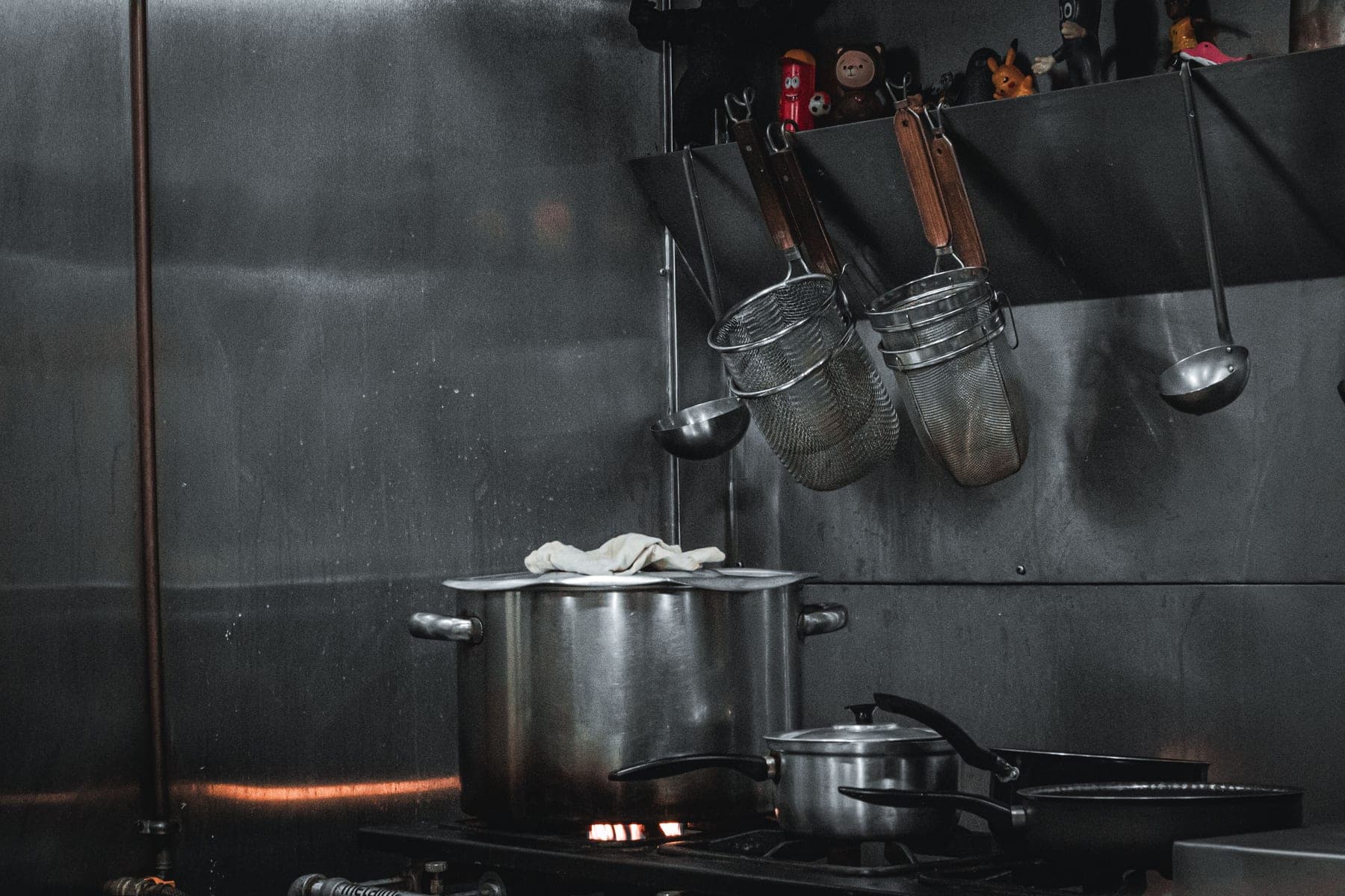 Stainless steel cookware set photographed straight-on under hard directional light