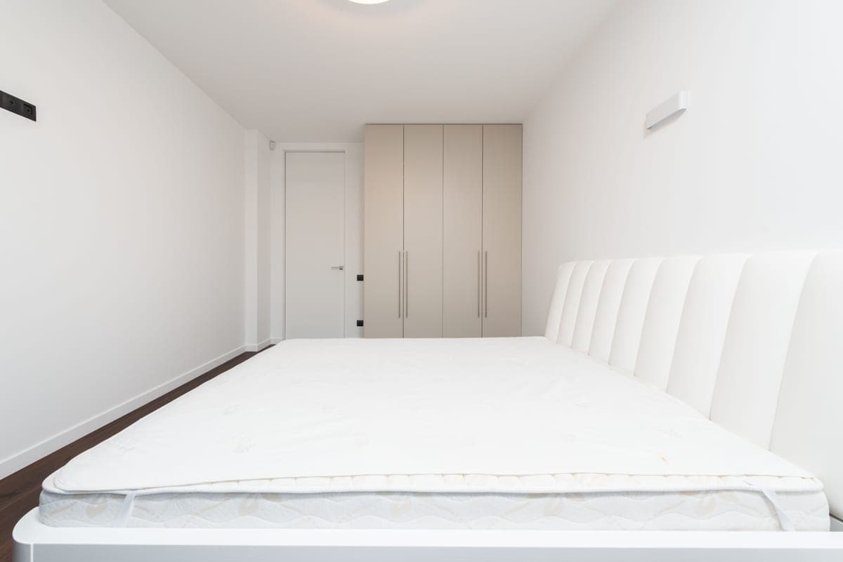 White mattress protector fitted on a bare mattress corner
