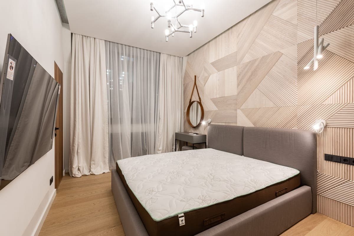 Bare mattress on a wooden bed frame in daylight