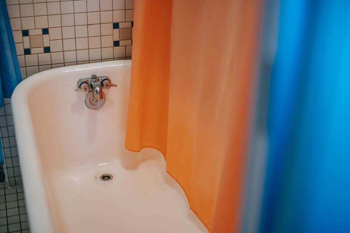 Fabric shower curtain hanging in a tiled bathroom
